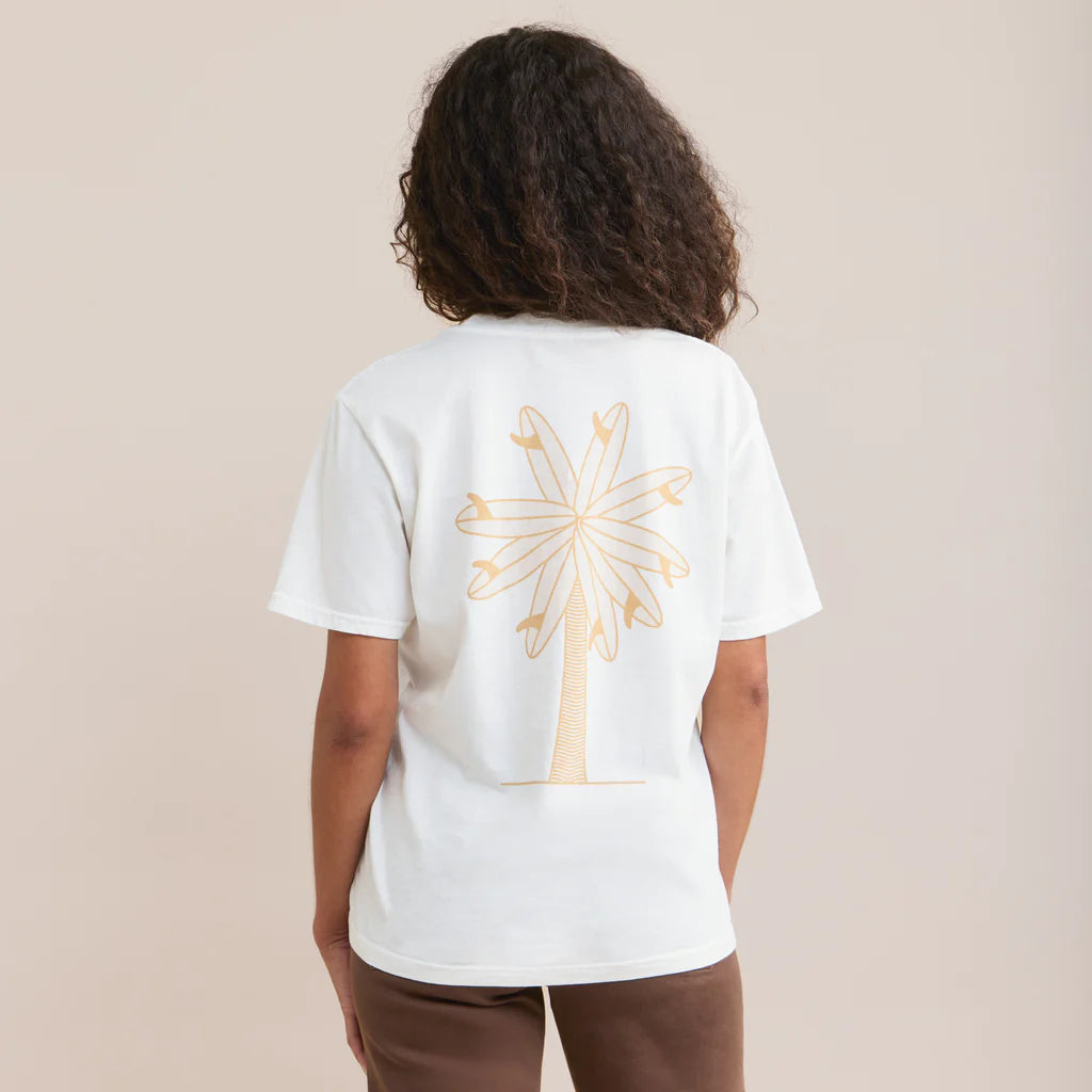 Polera color blanco con diseño trasero de una palmera con hojas de tablas de surf.
